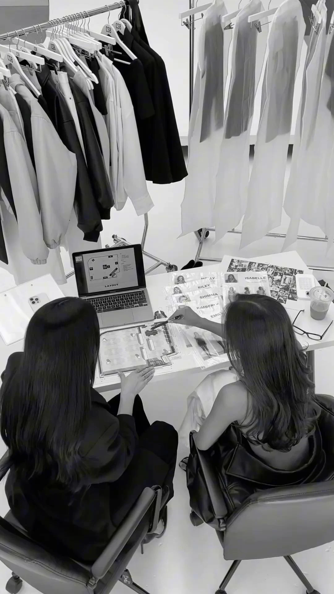 Two wardrobe stylists planning an engagement beside clothing rails