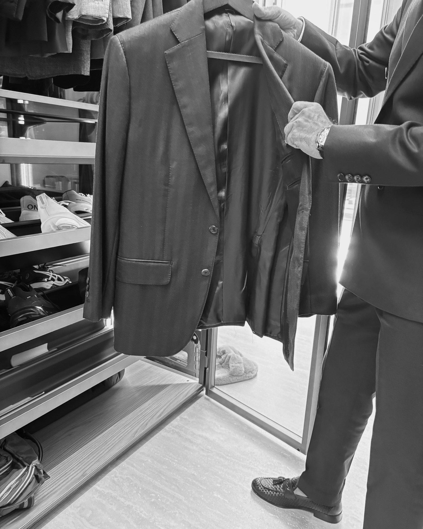 Wardrobe manager inspecting a tailored jacket inside a luxury closet