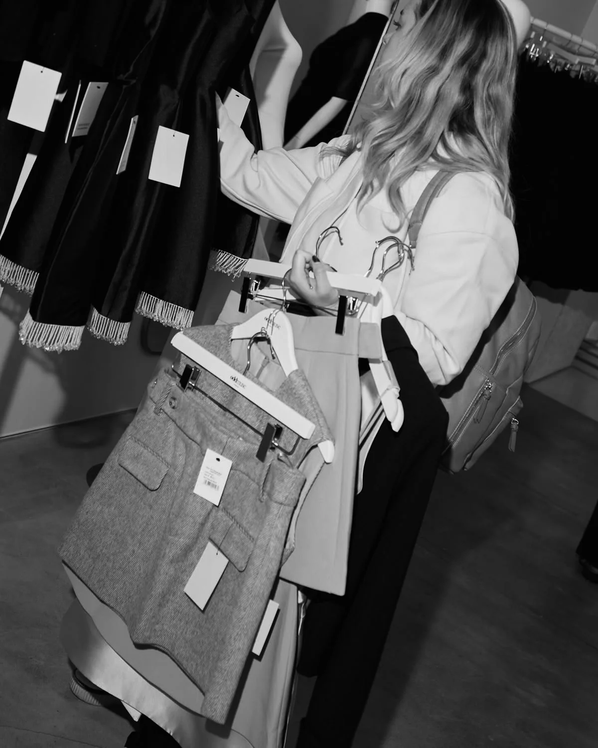 Personal shopper selecting garments and holding a collection of clothing on hangers