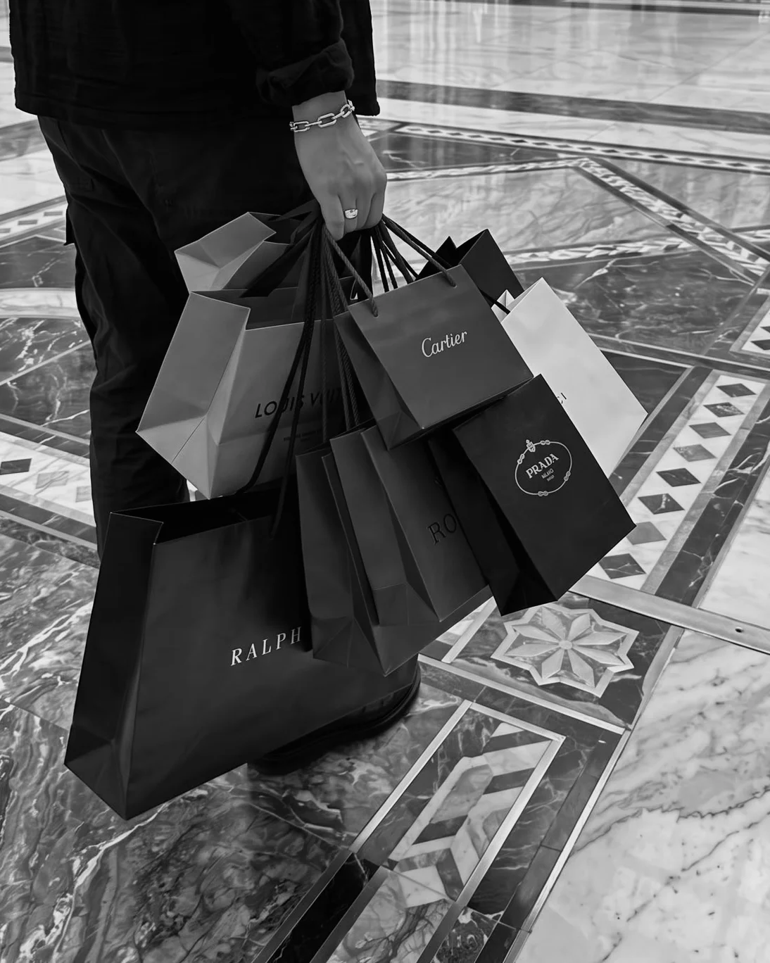 Luxury shopping bags carried across a patterned marble floor