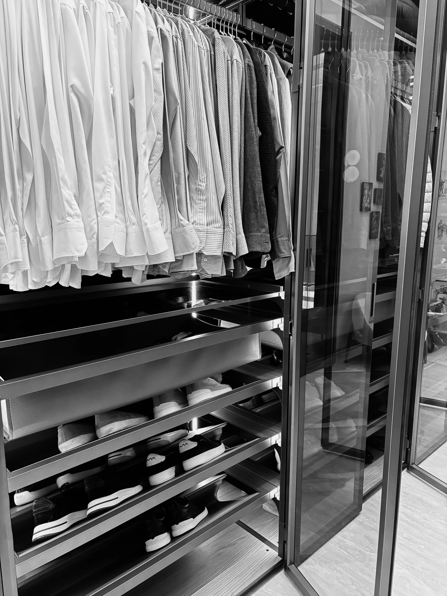 Organised wardrobe with shirts, tailoring and shoes behind glass doors