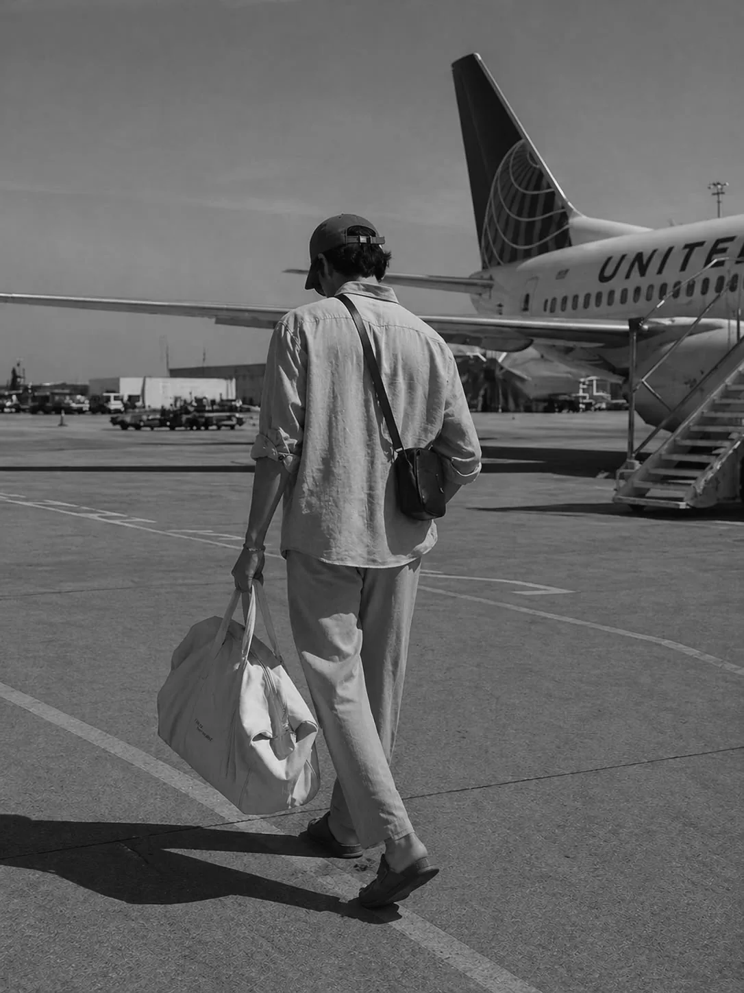 A traveller carrying a holdall across an airport apron toward a passenger aircraft